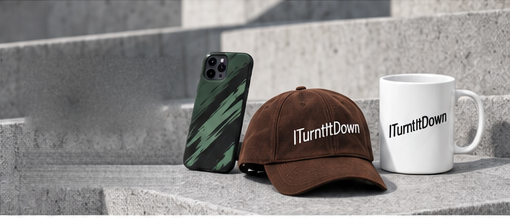 A forest green phone case, a brown cap and a white mug, all carrying the ITurntItDown wordmark, arranged on a concrete ledge