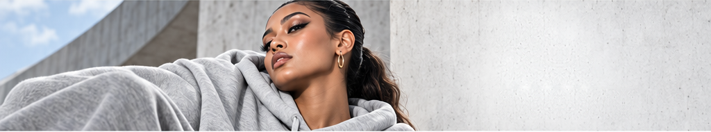 Model resting against a grey hooded sweatshirt on a concrete step