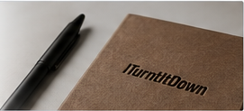 A pen resting on a kraft ITurntItDown notebook